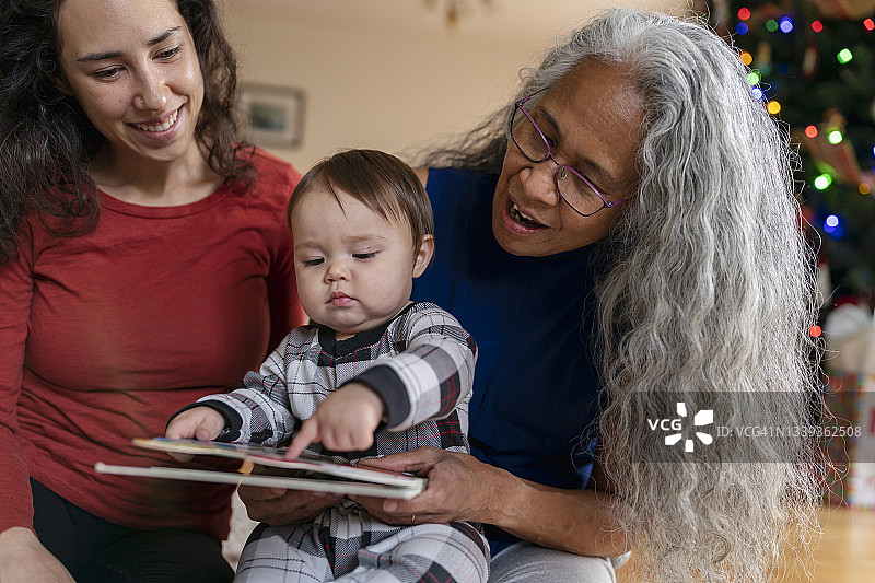 可爱的混血宝宝和妈妈、奶奶一起读书图片素材