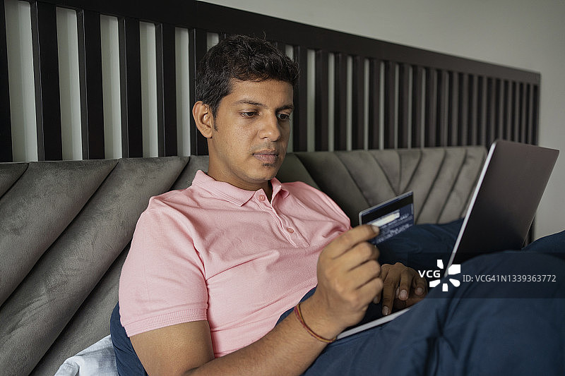 年轻男人在房间里用信用卡进行在线支付图片素材