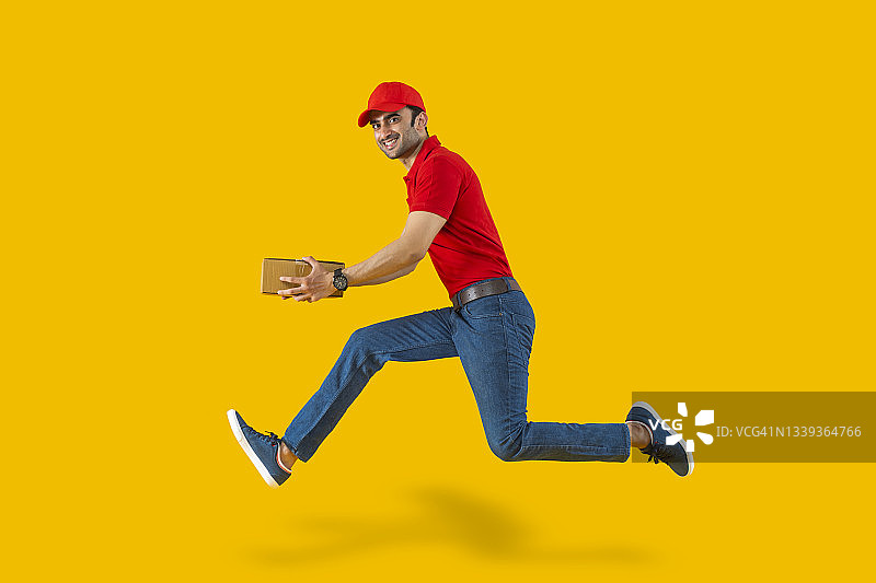 年轻送货员在纯色背景上奔跑搬运箱子的肖像照图片素材