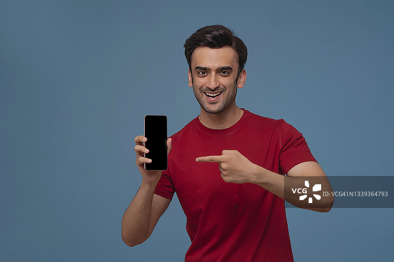 年轻男人在纯色背景下手持手机的肖像图片素材