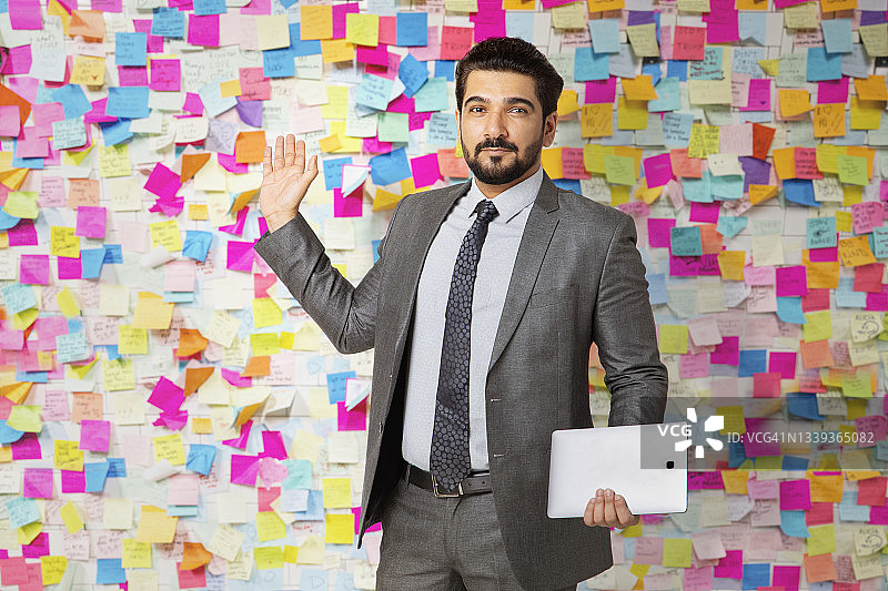 身穿正装的男人用平板电脑指向彩色便笺板图片素材