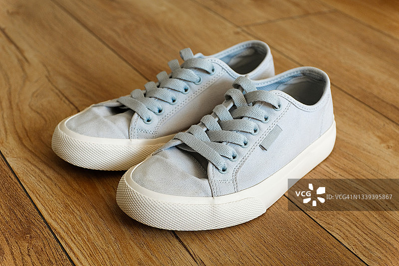 适合女性、青少年或女孩的全新干净现代运动鞋。家或室内木地板上的鞋子。时尚的生活方式。文本空间副本。图片素材