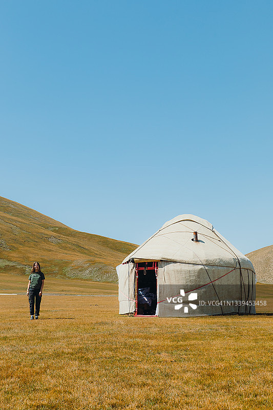 在吉尔吉斯斯坦山区毡房营地迎接早晨的年轻微笑女人图片素材