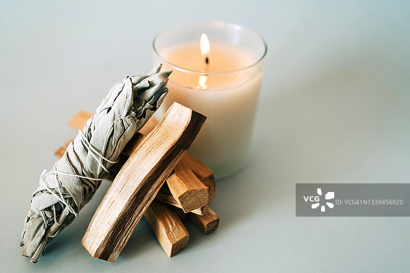 灰色背景上的圣木、白鼠尾草和燃烧的蜡烛，用于芳香疗法和仪式，可复制的设计空间，顶部视图和特写图片素材