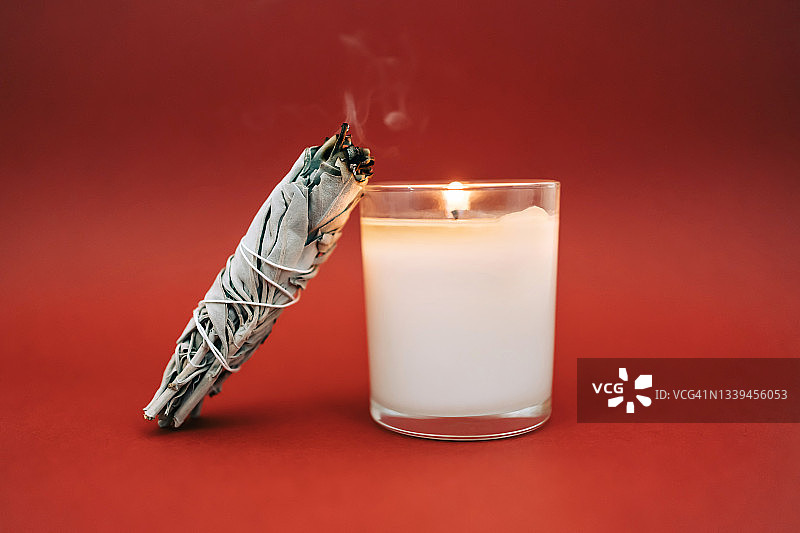 红背景鼠尾草烟熏与燃烧的蜡烛图片素材