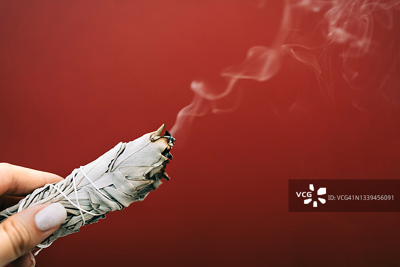 女士手持燃烧的白鼠尾草图片素材