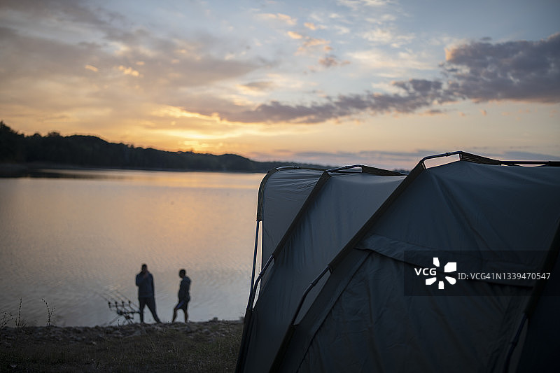 日落时在静止的湖面上进行鲤鱼垂钓露营图片素材