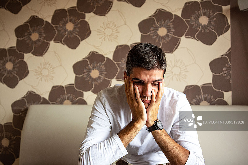 情绪低落的男人坐在床上，感觉不适图片素材