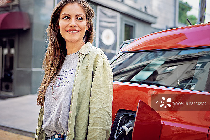为电动汽车充电的年轻女子肖像图片素材