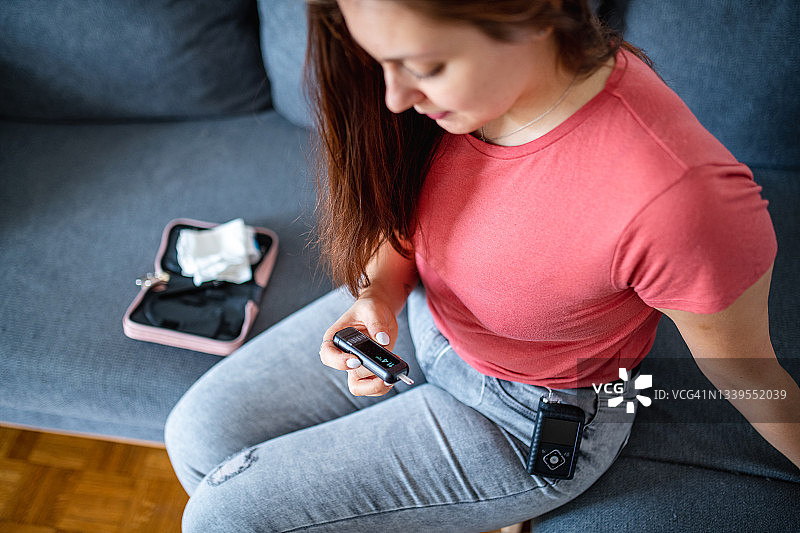 佩戴胰岛素泵并检查血糖仪的年轻女子图片素材