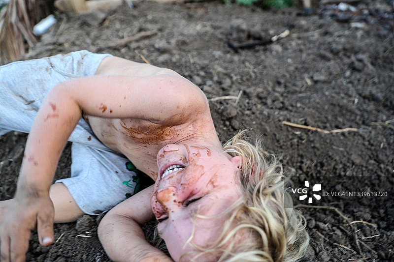 在泥土中打滚的脏污儿童图片素材
