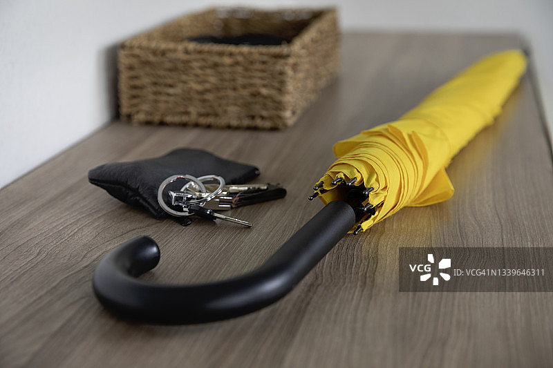 黄色雨伞、钱包和钥匙放在家庭走廊的边桌上图片素材