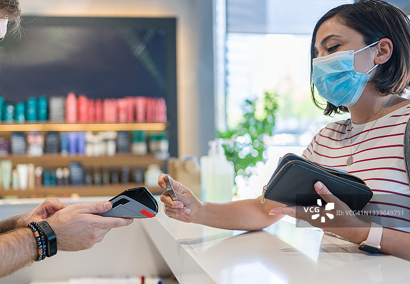 戴防护面罩的女人用非接触式卡支付图片素材