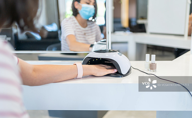 美容院女顾客将手放入UV灯烘干机图片素材