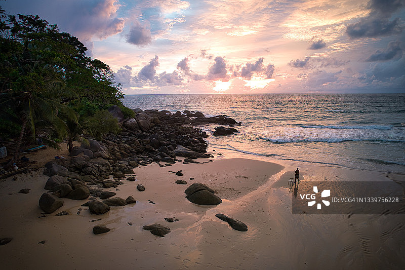 旅行者在泰国普吉岛卡塔诺伊海滩日落时拍摄美丽岩石海滩的照片图片素材