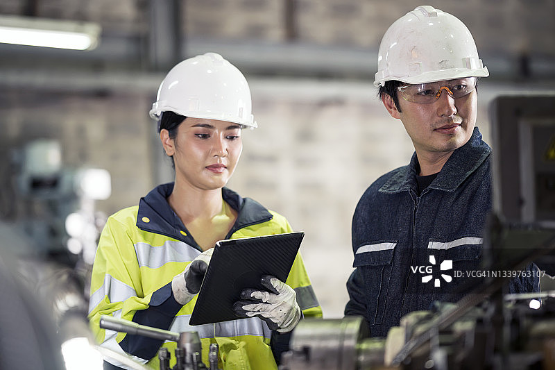 评估员工绩效：女主管观察数控机床操作员，以提高其技能水平图片素材