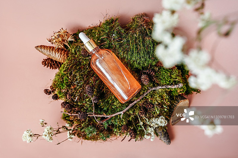 带有滴管的精华液玻璃瓶与苔藓鲜花等自然装饰品的组合图片素材