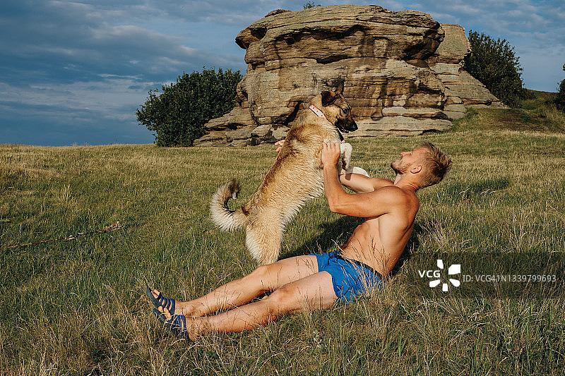 快乐的男人和他的狗在休息，与宠物一起度假，在自然中与宠物玩耍图片素材