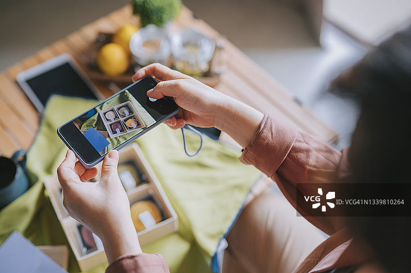 俯视：中国亚洲女性在客厅用手机拍摄朋友送的月饼礼盒图片素材