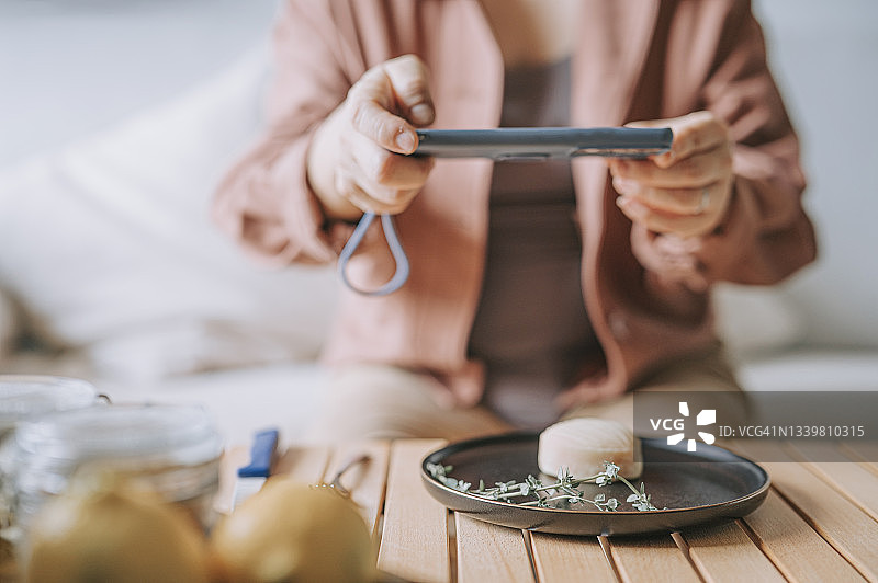 中国女性在客厅用手机拍摄朋友送的月饼礼盒图片素材