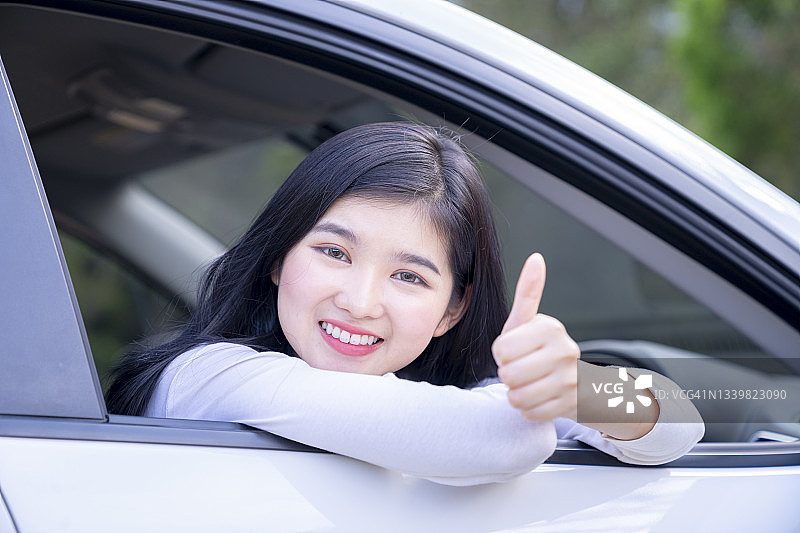 年轻女子在车里竖起大拇指的 портрет，汽车保险概念图片素材