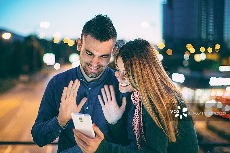 幸福的夫妇在桥上进行视频通话图片素材
