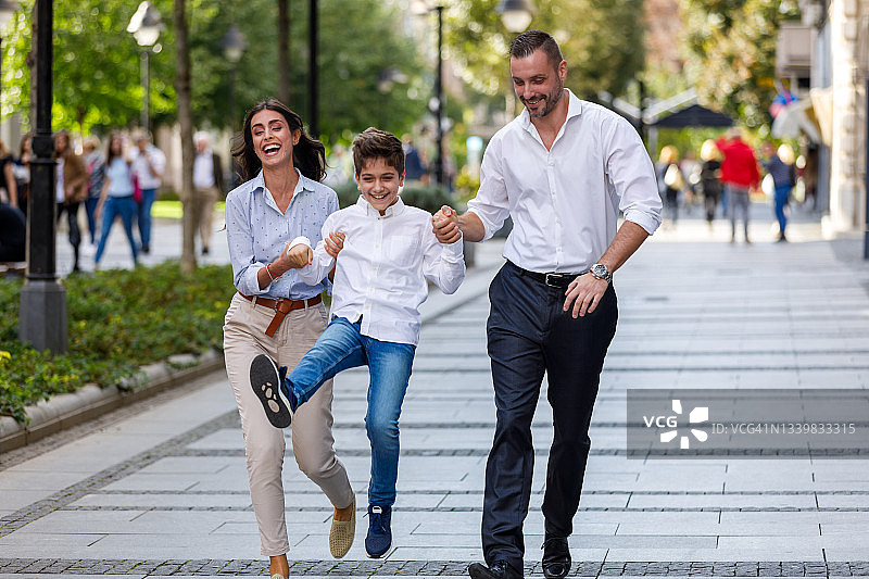 幸福的一家人在阳光明媚的日子里牵手走过城市图片素材