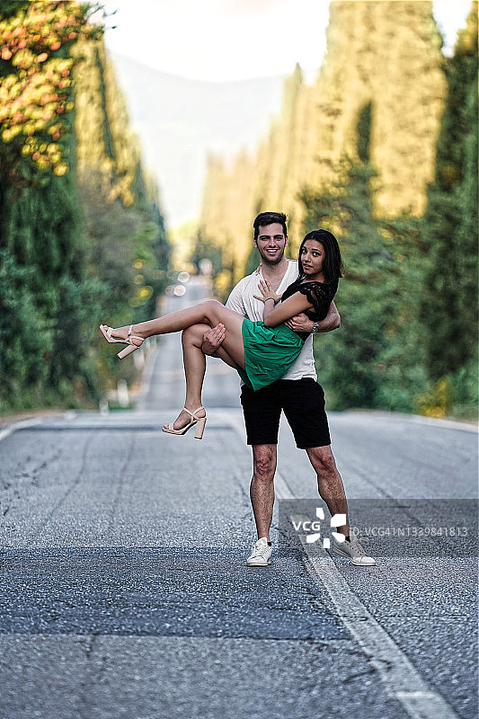 快乐的年轻夫妇在博尔盖里柏树大道上图片素材