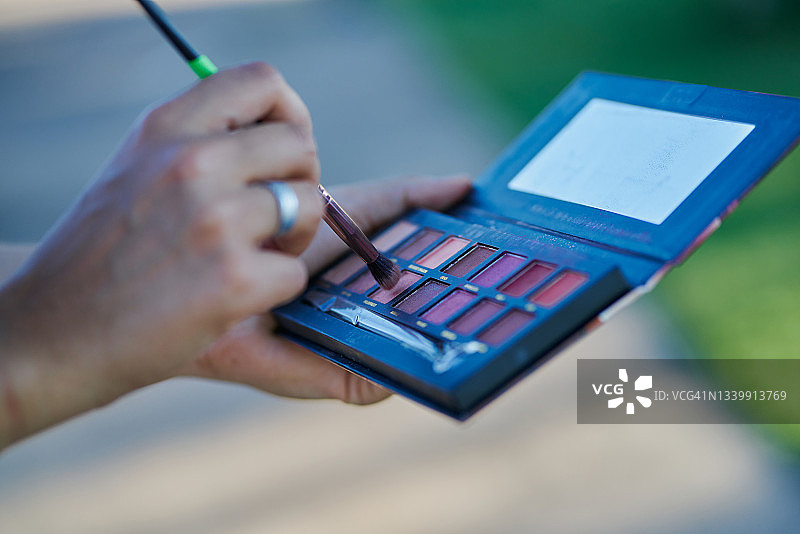 化妆师拿着带镜子和刷子的化妆盘图片素材