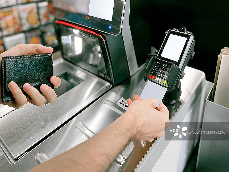 男人在杂货店将信用卡插入读卡器图片素材