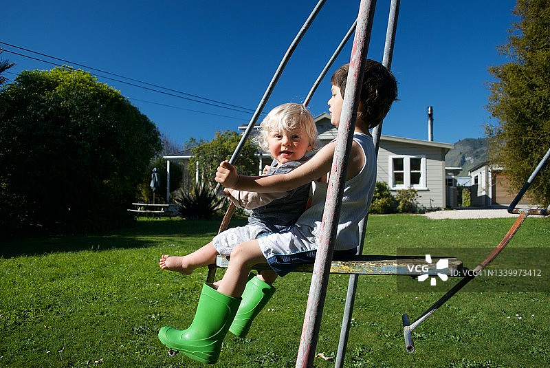 新西兰儿童在花园里使用经典奇异果摇摆图片素材