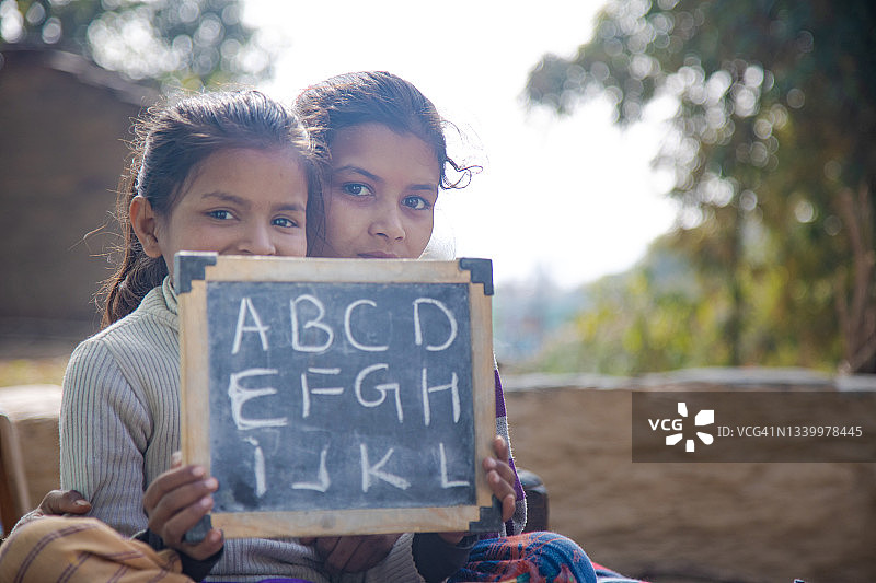 印度乡村女孩在黑板上写英文字母图片素材