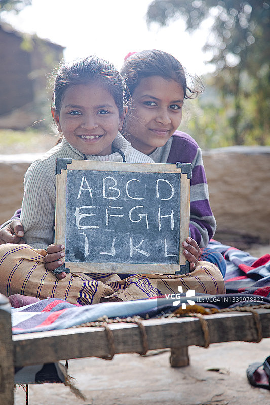 乡村女学生手持写有英文字母的石板图片素材