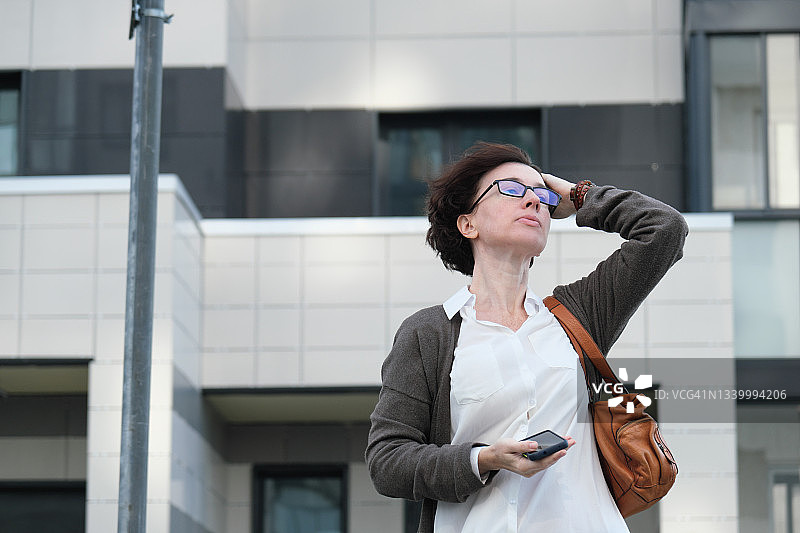 女子在城市建筑旁等待图片素材