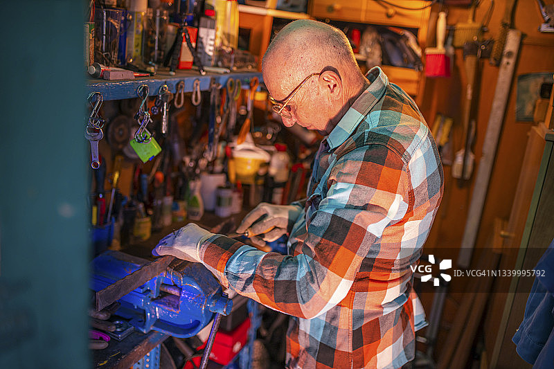 正在处理金属部件的年长工人图片素材