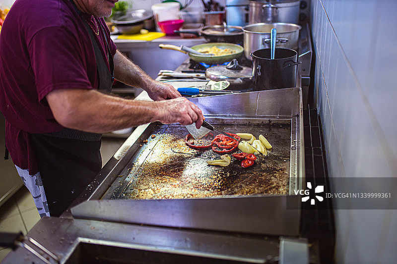 熟练的资深厨师在餐厅厨房烤蔬菜图片素材