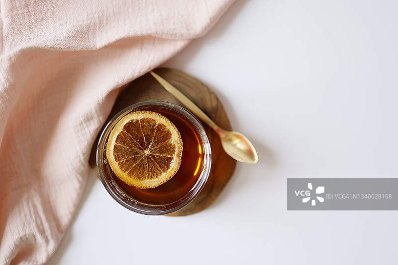 一杯红茶，配木制杯垫上的橘子片图片素材