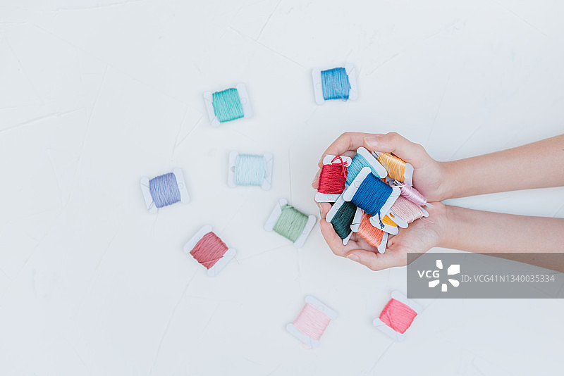 俯视角度：充满棉线的年轻白人女孩双手图片素材