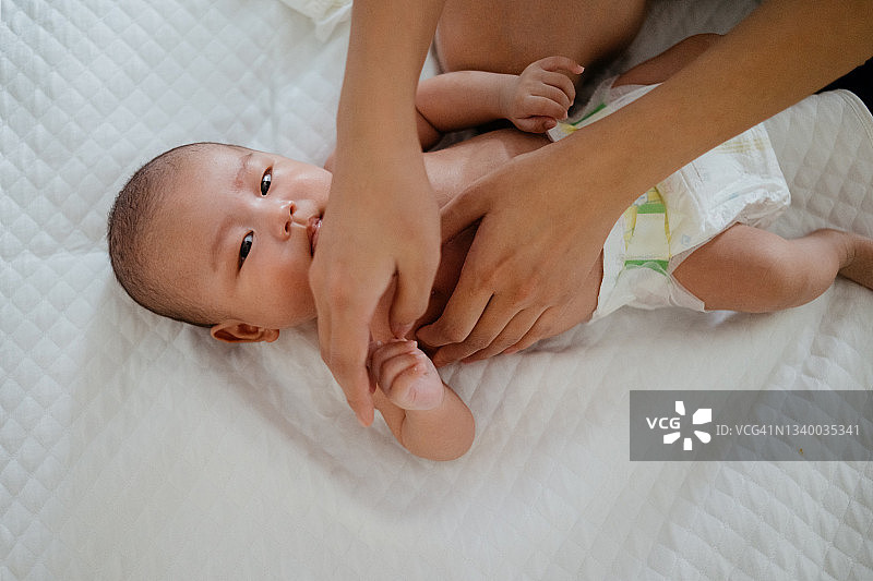 亚洲妈妈洗澡后为宝宝涂抹身体乳图片素材