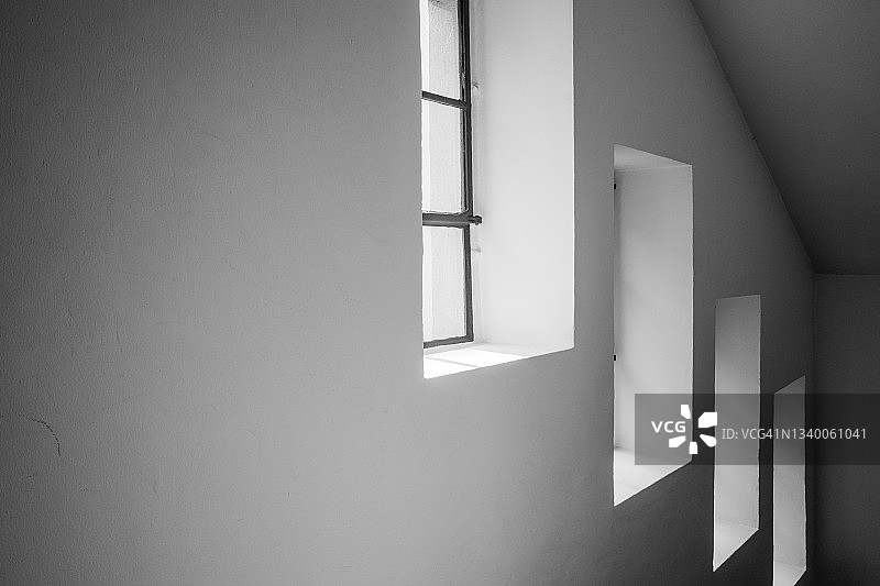 楼梯墙壁上三个方形窗户的黑白室内景观图片素材