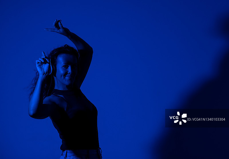 在蓝色背景下听音乐的年轻女人图片素材