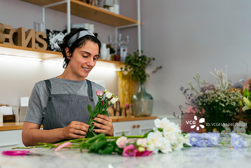 年轻女花艺师在工作室里制作花束图片素材