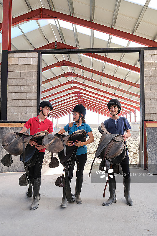母亲和两个儿子拿着马鞍，微笑交谈图片素材