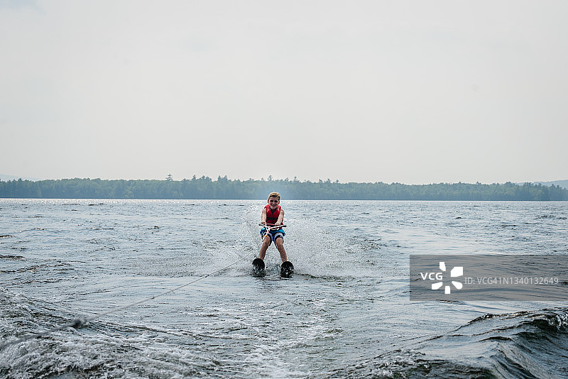 在湖上滑水的青少年男孩，背景是树木图片素材