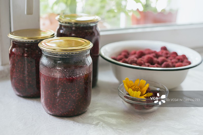 覆盆子果酱玻璃罐和红色覆盆子碗图片素材