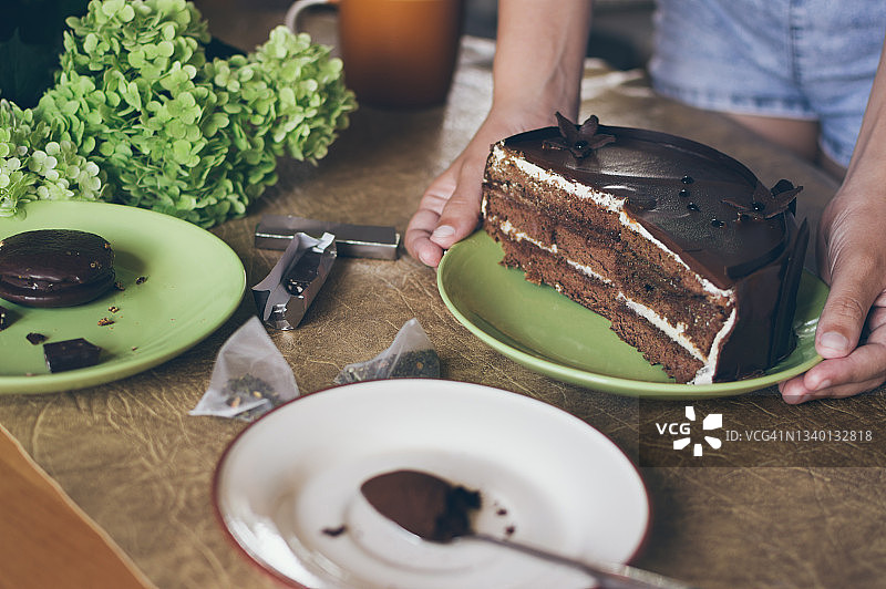 手将装有巧克力蛋糕的盘子放在桌子上图片素材