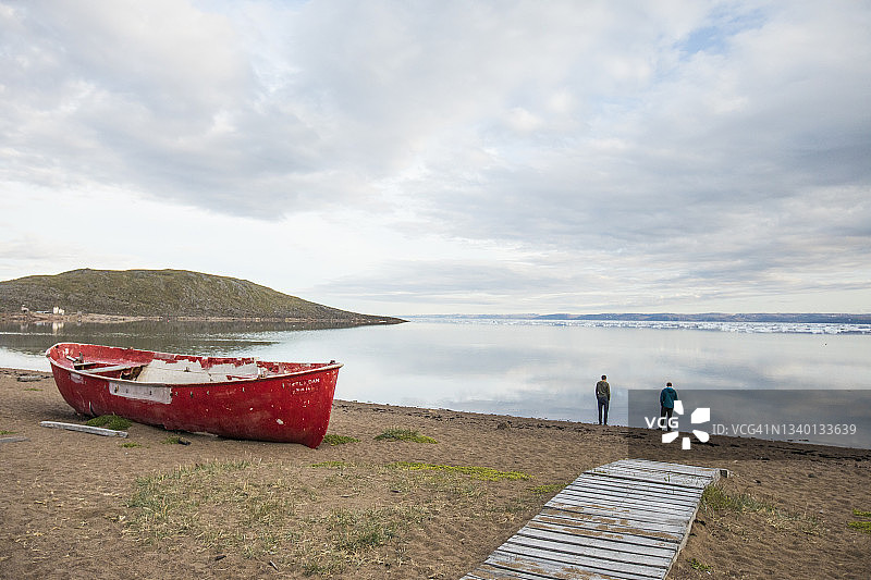 两个男人站在加拿大伊卡卢伊特海岸边观看冰山图片素材