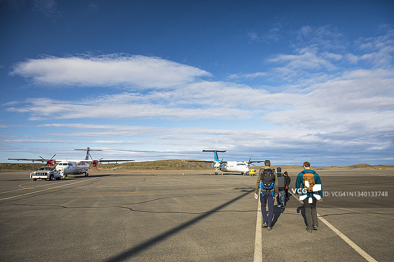 乘客走在停机坪上，走向机场的一架小型飞机图片素材