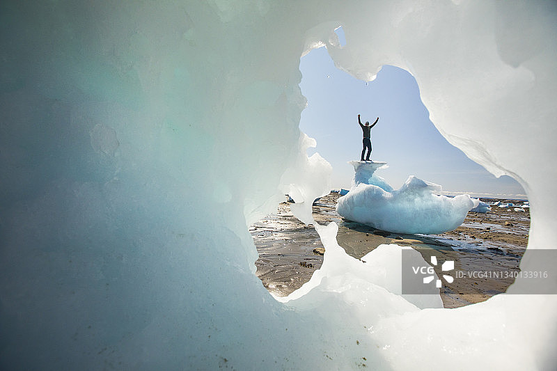 男人站在冰山顶上，举起双臂，巴芬岛图片素材