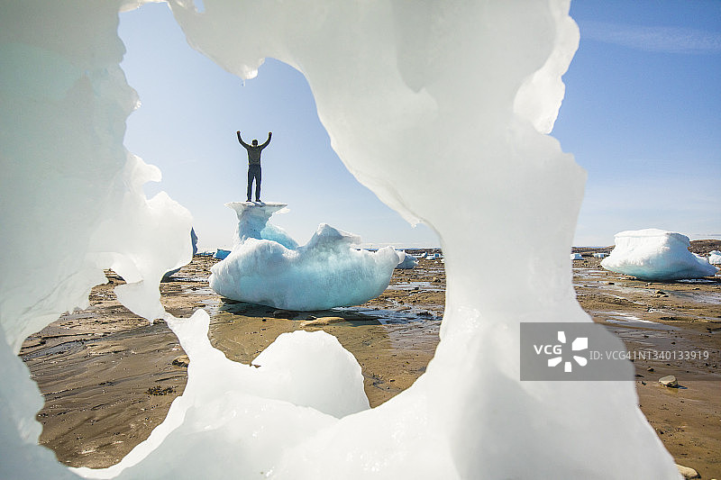 男人站在冰山顶上，举起双臂，巴芬岛图片素材